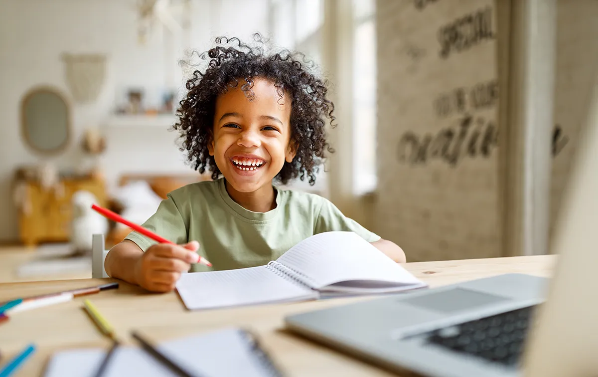 a young boy smiling and studying at home
