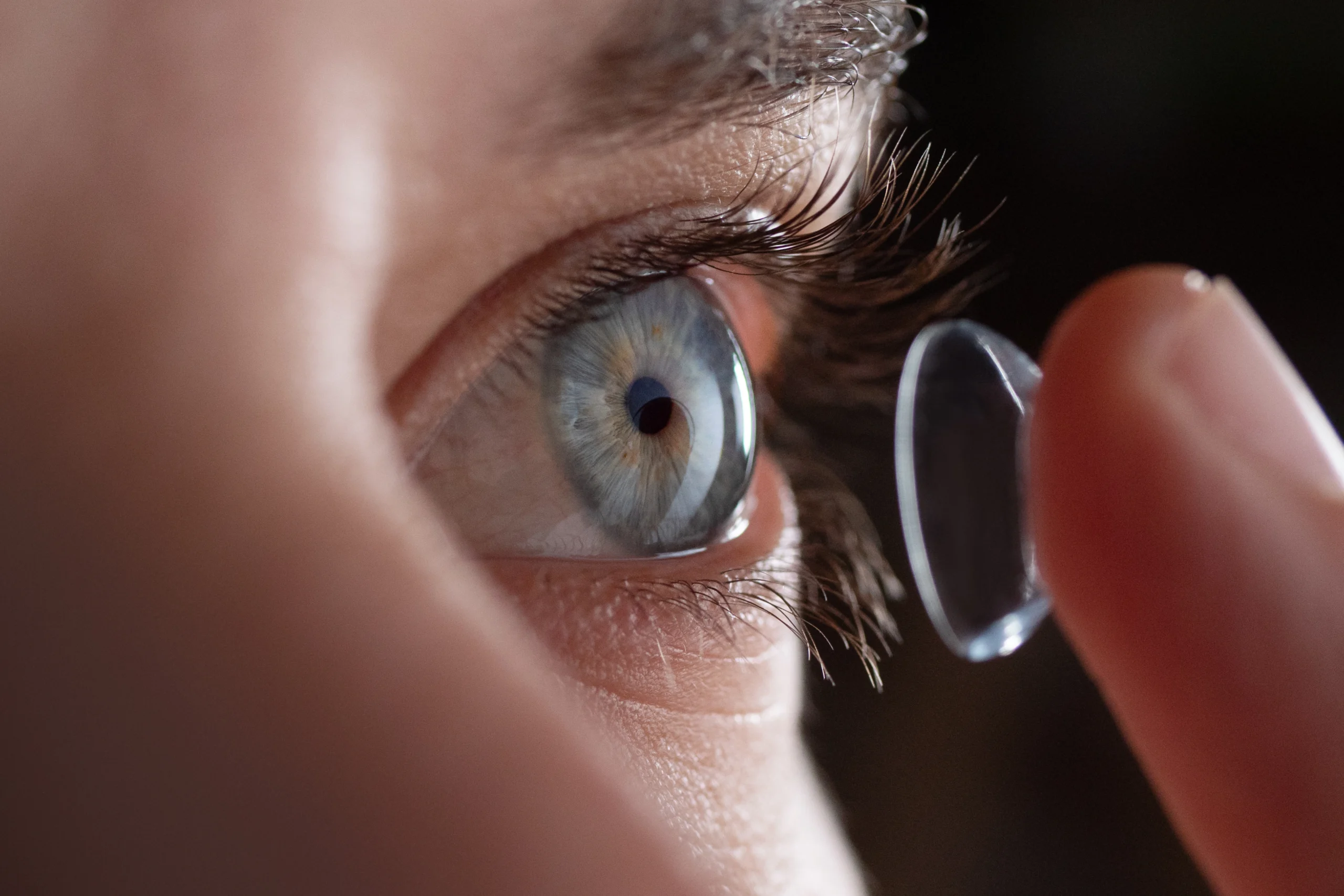 A close up of a woman putting in a contact lens.
